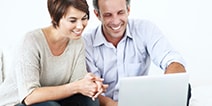 Couple smiling while looking at laptop