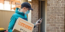 delivery guy carrying a parcel and looking at his mobile phone